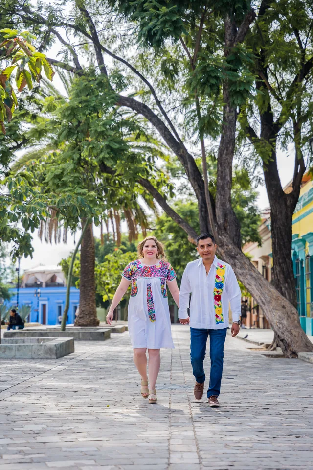 Maria Esthela y Pablo caminando de la mano bajo los árboles