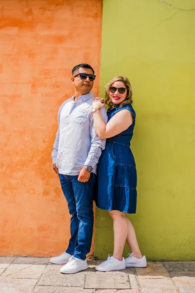 Maria Esthela y Pablo frente a un muro naranja y verde